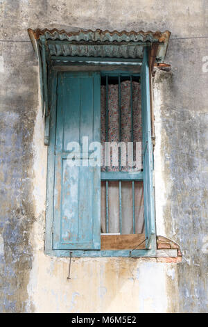 Ein geöffnetes Fenster mit Gitter und ein Blech Dach in der Fassade eines alten Hauses, Penang, Malaysia. Stockfoto