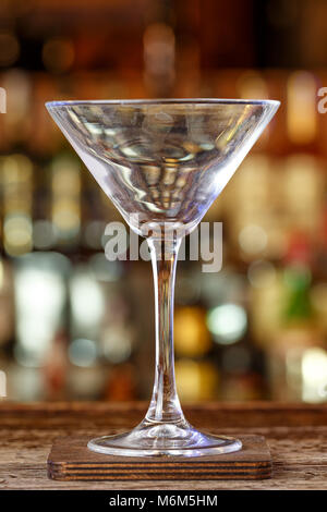 Eine saubere Martini Glas steht auf den unscharfen Hintergrund der Theke, eine traditionelle Bar Hintergrund Stockfoto