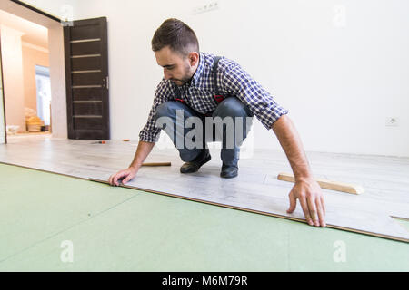 Tischler Arbeiter installieren Parkett Board während der Arbeit mit Hammer Bodenbelag Stockfoto