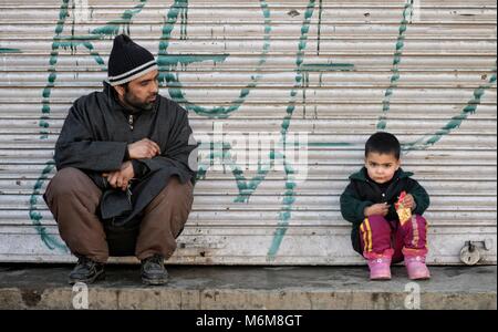 Srinagar, Indien. 10 Feb, 2017. Ein Kaschmirischen Kind zusammen mit seinem Vater sitzen vor ihren closed shop unter Ausgangssperre wie Beschränkungen durch Behörden auferlegt wurden Menschen aus Holding JRL sogenannte Proteste in der Innenstadt von Srinagar, die Hauptstadt des indischen Teil Kaschmirs gesteuert zu verhindern. Den gemeinsamen Widerstand Führung (JRL), bestehend aus Syed Ali Shah Geelani, Umar Mirwaiz Farooq und Mohammad Yasin Malik für Abschaltung am Montag gegen die Shopian Morde aufgerufen hatte. Credit: Bilal Ahmad/Pacific Press/Alamy leben Nachrichten Stockfoto