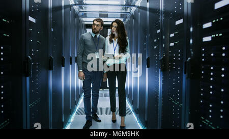 IT-Spezialisten zeigen Arbeiten im Rechenzentrum mit Reihen von Rack-servern auf Seine weiblichen Kollegen. Stockfoto