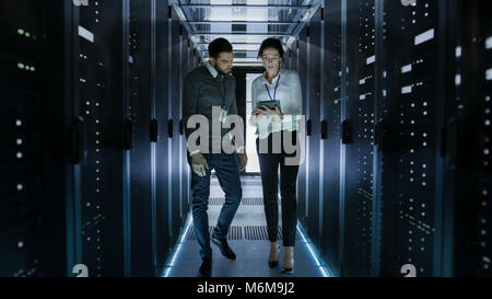 Männliche und weibliche Server Techniker arbeiten im Rechenzentrum. Rack Server Diagnostics ausgeführt. Frau nutzt Tablet Computer. Stockfoto