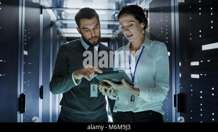 Zwei IT-Ingenieure im Rechenzentrum/Serverraum, Reden, Diagnostics mit Tablet-PC. Stockfoto