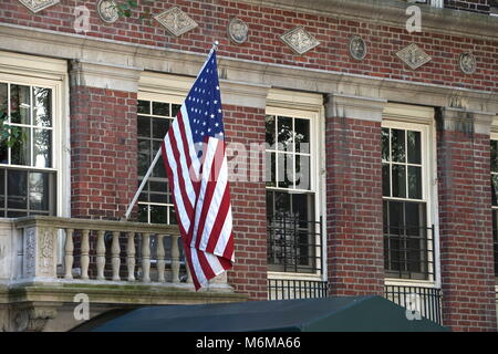 Amerikanische Flagge hängt über dem Eingang zu einem städtischen Gebäude im traditionellen Stil. Patriotische Unterstützung Stockfoto