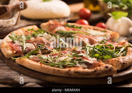 Köstliche italienische Pizza mit Rucola Parmaschinken auf hölzernen Tisch Stockfoto