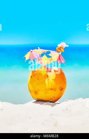 Kokosnuss mit bunten Sonnenschirmen und Strohhalme an einem Strand, Sommer Spaß Urlaub Konzept, selektive konzentrieren. Stockfoto