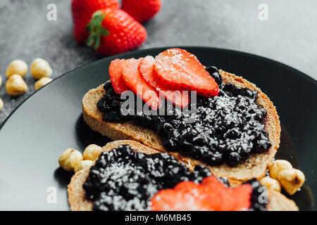 Blueberry jam auf Brot mit in Scheiben geschnittene Erdbeeren Stockfoto