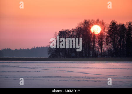 Einen malerischen Sonnenuntergang mit großen Sonne im Winter abends in Finnland Stockfoto