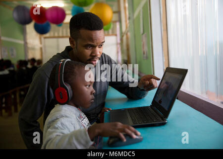 Lehrer helfen eine Schule junge Kind auf einem Laptop in der Klasse Stockfoto