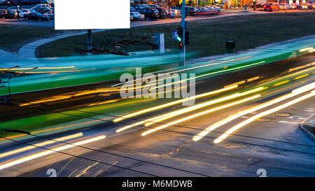 Leere Anschlagtafel auf Nacht city street, mockup. Leichte Spuren von vorbeifahrenden Autos durch die Straßen der Nacht Stadt. Stockfoto