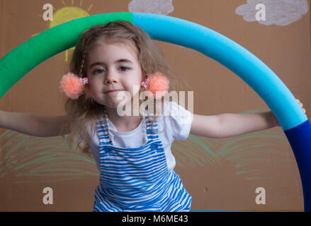 Mädchen spielen mit einem hoola Hoop. Hintergrund Der gemalte Sonne und weiße Wolken Stockfoto