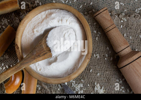 Reis Mehl in eine olivenholz Platte auf einem Sack. Stockfoto