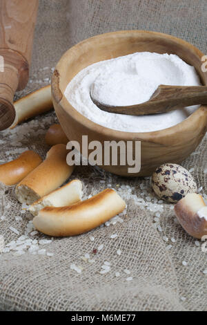 Reis Mehl in eine olivenholz Platte auf einem Sack. Stockfoto