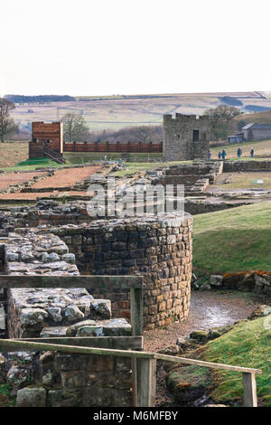 Vindolanda Roman Fort, Blick von der Reste eines römischen Badehaus in Richtung einer rekonstruierten Abschnitt der Hadrian's Wall im Vindolanda Ausgrabungsstätte Stockfoto
