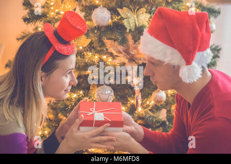 Mann und Frau Geschenk Exchange Vor geschmückten Weihnachtsbaum. Liebe und Urlaub Konzepte. Stockfoto
