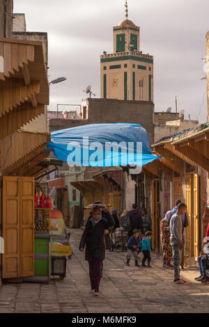 Eine Straßenszene in der Moulay Abdallah Viertel von Fes El Jedid, Fes, Marokko, zeigt die Moschee im Hintergrund Stockfoto