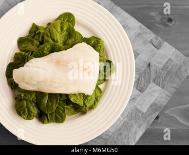 Einfaches Mittagessen von organischen Spinat auf weiße Platte und auf Holz Schneidebrett platziert Stockfoto