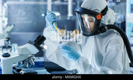 Medizinische Virologie Wissenschaftler arbeitet in einem Gefahrgut-Anzug mit Maske, nutzt sie Pipette. Sie arbeitet in einem sterilen High-Tech-Labor Stockfoto