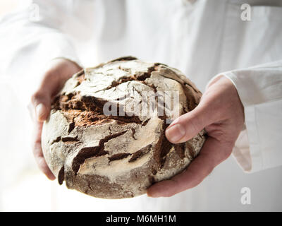 Detailansicht der männlichen Hände halten einen frisch gebackenen runde Land Brot Stockfoto