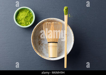 Matcha, grüner Tee Pulver in schwarz Schüssel mit bambusbesen auf schiefer Hintergrund. Ansicht von oben. Kopieren Sie Platz. Stockfoto