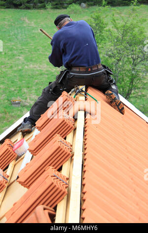 Arbeiten an wechselnden alte Dachziegel, Neue. Auf dem Dachfirst ist ein Handwerker Montage Dach eave blinken. Stockfoto