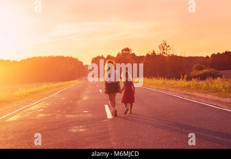 Silhouette zwei kleine Mädchen zu Fuß auf der Straße. Schwestern genießen einen Urlaub über verschwommenes Sommer Natur. Konzept Menschen und Natur. Stockfoto