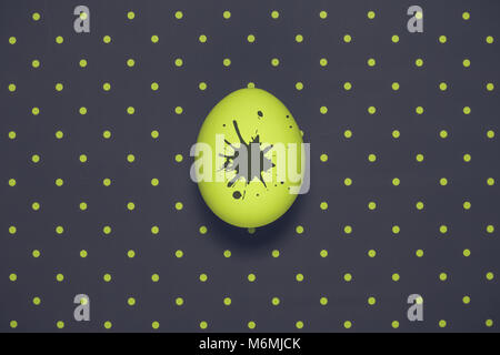Neon Grün Ei mit Farbe Flecken auf dunklem polka Hintergrund minimalistischen Konzept Stockfoto
