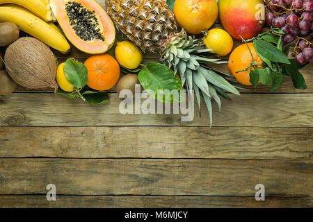 Top Obere Grenze mit Kopieren aus frischen tropischen Früchte Ananas Papaya Mango Coconut Orangen, Kiwi, Bananen, Zitronen Pampelmusen und Grapefruits auf Holz Hintergrund. Stockfoto