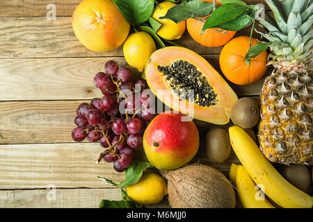 Seite Grenze mit Kopieren aus frischen tropischen Früchte Ananas Papaya Mango Coconut Orangen, Kiwi, Bananen, Zitronen Pampelmusen und Grapefruits auf Holz Hintergrund. Gesundheit Stockfoto
