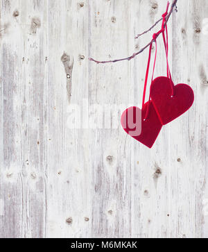 Zwei rote Herzen, hängend an einer Niederlassung über die alten hölzernen Hintergrund. Stockfoto