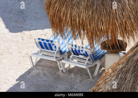 Blick auf einen tropischen Sandstrand mit Sonnenschirmen und Liegestühlen. Stockfoto