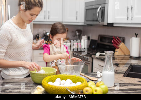 Glückliche Familie in der Küche, die Mutter und Tochter kochen Apfelkuchen, Mixen von Teig Stockfoto