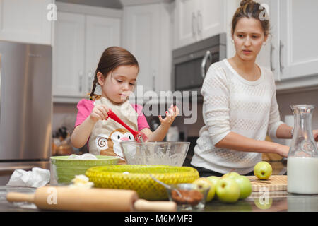 Glückliche Familie in der Küche, die Mutter und Tochter kochen Apfelkuchen, Mixen von Teig Stockfoto