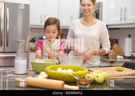 Glückliche Familie in der Küche, die Mutter und Tochter kochen Apfelkuchen, Mixen von Teig Stockfoto