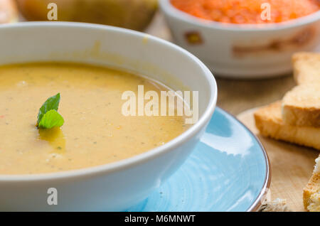 Die linsensuppe im weißen Platten ist auf dem Tisch. Es gibt Linsen, Karotten, Zwiebeln, Brot auf dem Tisch. Stockfoto