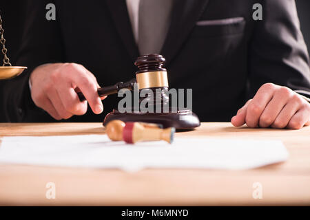 Nahaufnahme der männlichen Anwalt oder Richter hand Anschlagen der Hammer auf klingende blockieren. Recht und Gerechtigkeit Konzept. Stockfoto