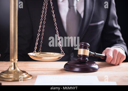 Nahaufnahme der männlichen Anwalt oder Richter hand Anschlagen der Hammer auf klingende blockieren. Recht und Gerechtigkeit Konzept. Stockfoto