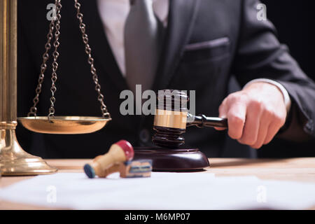 Nahaufnahme der männlichen Anwalt oder Richter hand Anschlagen der Hammer auf klingende blockieren. Recht und Gerechtigkeit Konzept. Stockfoto