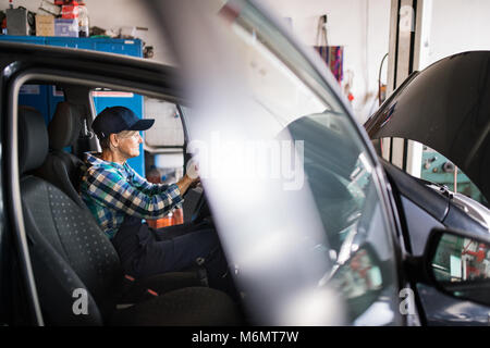 Senior Mechanikerin Instandsetzung ein Auto in eine Garage. Stockfoto