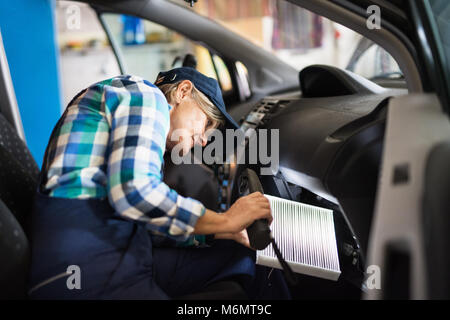 Senior Mechanikerin Instandsetzung ein Auto in eine Garage. Stockfoto