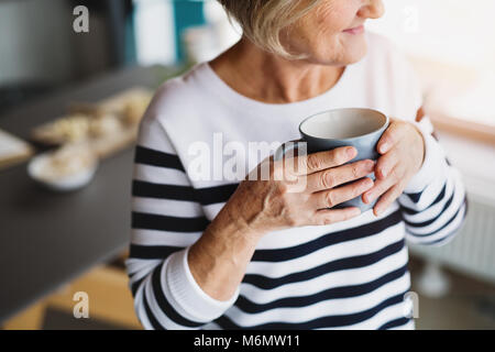 Ältere Frau mit einer Tasse Kaffee in der Küche. Stockfoto