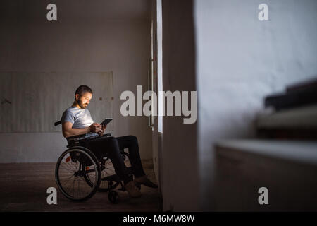 Mann im Rollstuhl arbeiten mit Tablet. Stockfoto