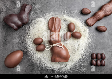 Leckere Schokolade Osterhasen und Eier in einem Nest auf rustikalen Hintergrund Stockfoto