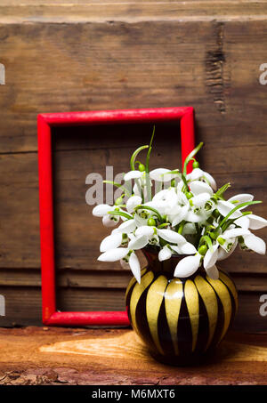 Snowdrop Blumen in einer Vase gegen rustikalen Holzmöbeln Hintergrund Stockfoto