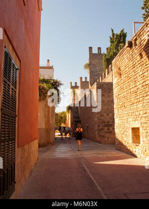 Frau zu Fuß in Richtung auf einem Pferd durch einsame Straßen von Alcudia Altstadt in der Morgensonne Stockfoto