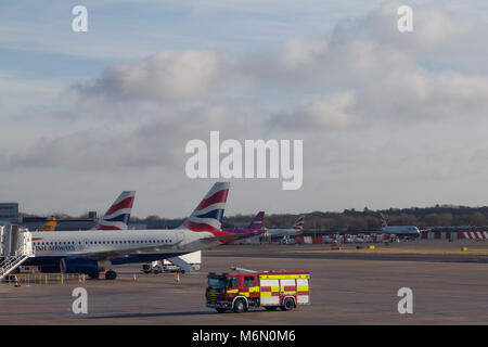 Ein Feuerwehrmotor vor British Airways-Flugzeugen am Flughafen Gatwick, London, Großbritannien. Stockfoto