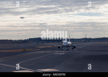 Ein Boeing 737-800-Flugzeug taxiert zur Startbahn, wenn ein weiteres Flugzeug auf dem Narita International Airport, Tokio, Japan, landet Stockfoto