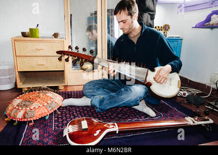 Junge Mann spielt klassische indische Musik auf einer Sarod zu Hause im Stadtteil Albaicin Granada, Andalusien, Spanien. Stockfoto