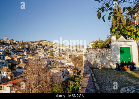 Zwei junge Frauen sitzen in La Churra square Aussichtspunkt an der Unesco Albaicin Altstadt suchen. Granada, Andalusien, Spanien Stockfoto