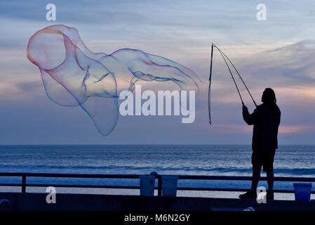 Männliche Schauspieler, groß, große Seifenblasen bei Sonnenuntergang mit Blick auf den Pazifik, Pacific Beach, San Diego, Kalifornien, USA. Stockfoto